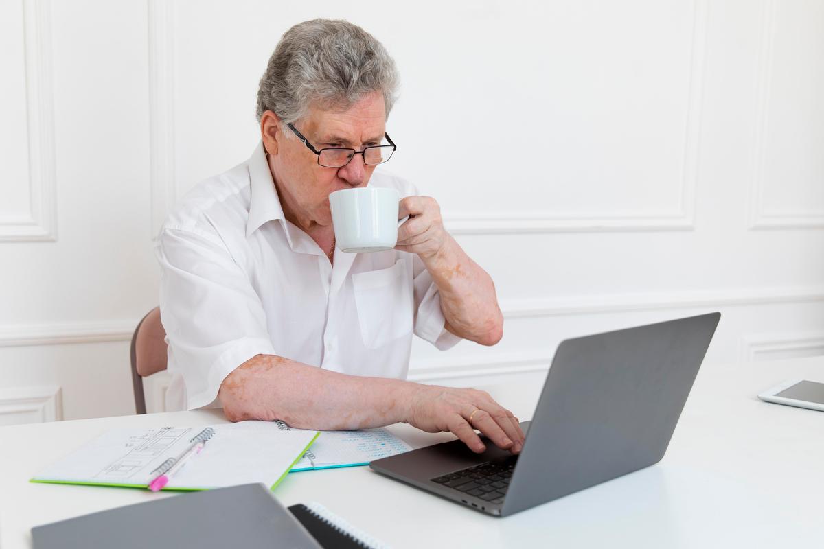 Freepik, homme âgé avec des documents devant un ordinateur