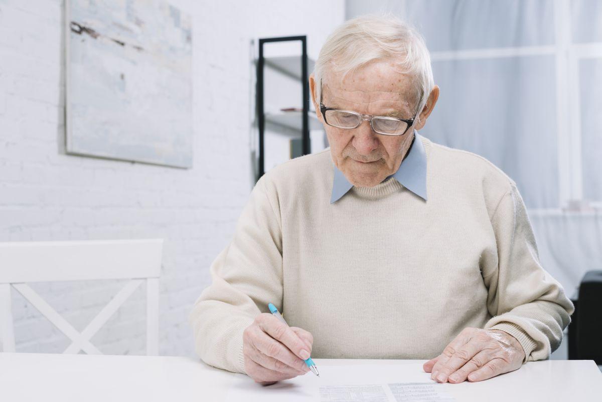 Freepik, homme âgé qui remplit un document