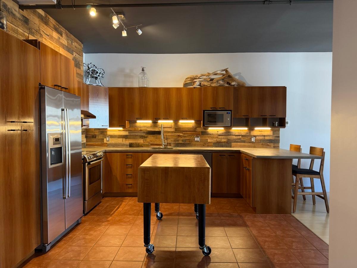 La cuisine aux comptoirs de béton et son îlot généreux