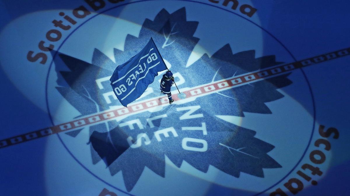 Young fan stand on the ice and wave a flag before a Maple Leafs' game.