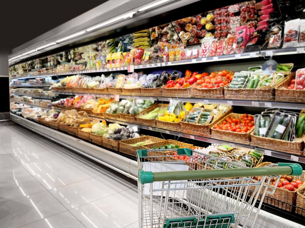 Panier d'épicerie devant un rayon de fruits et légumes 